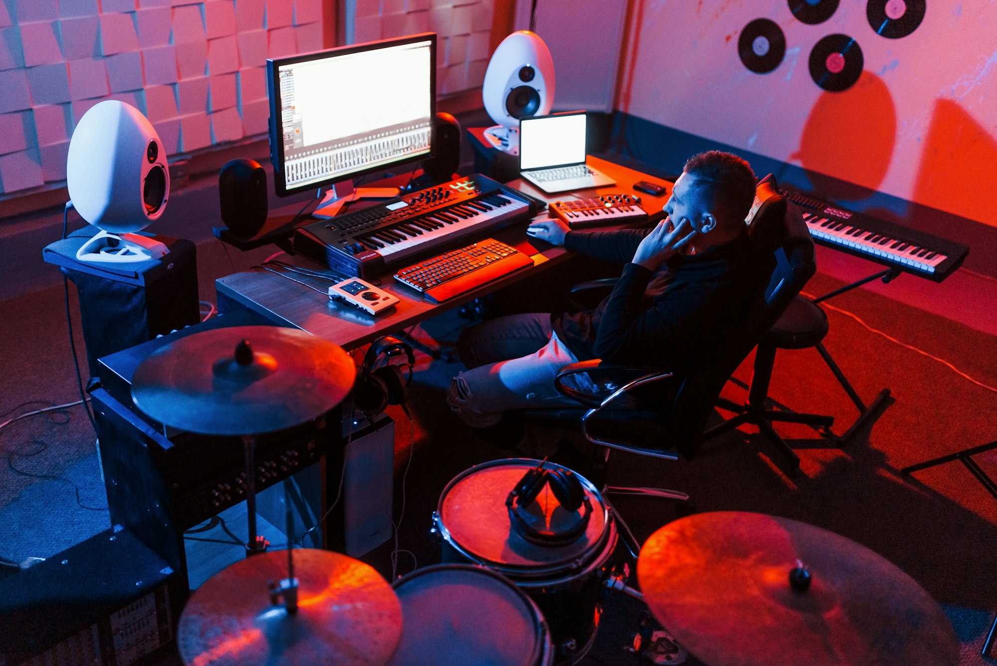 Sound engineer working and mixing music indoors in the studio near drum kit